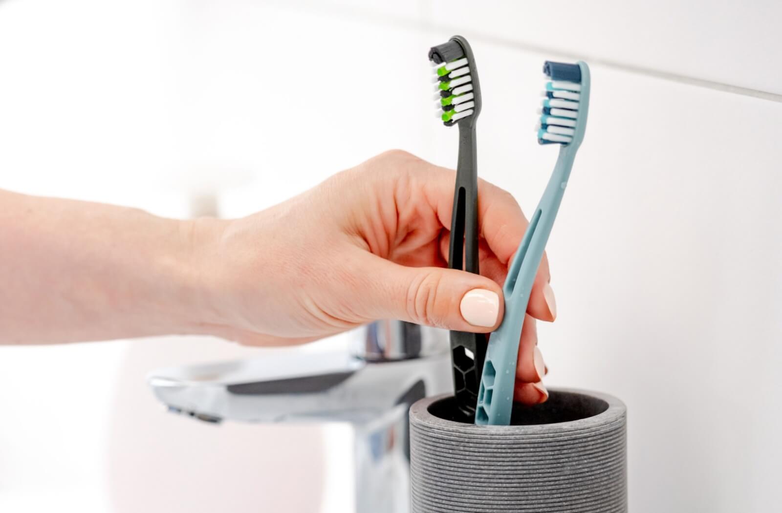 Close-up of toothbrushes in a holder, showing different brush heads.